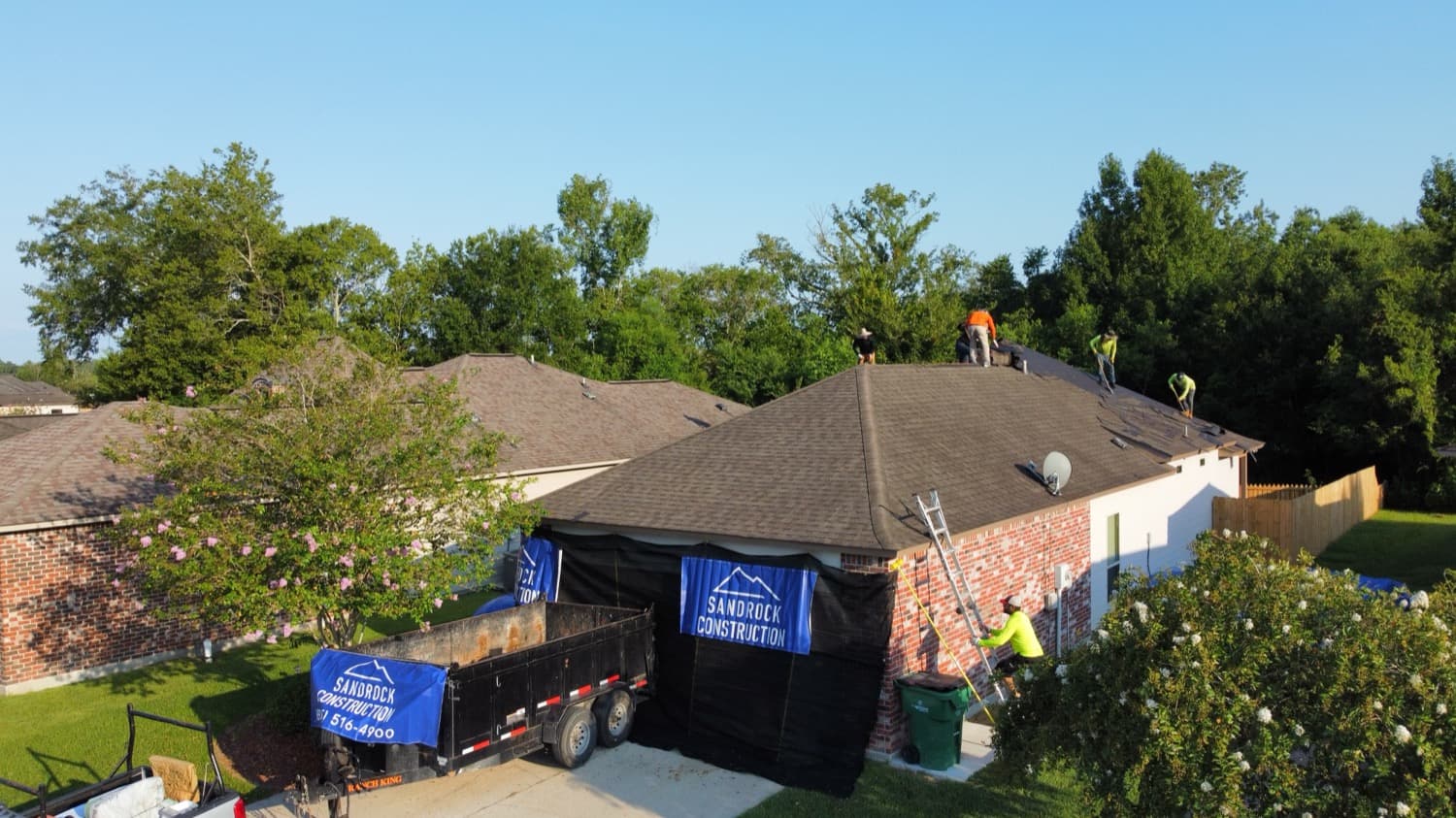 Sandrock Construction crew installing a new roof with branded protection in place