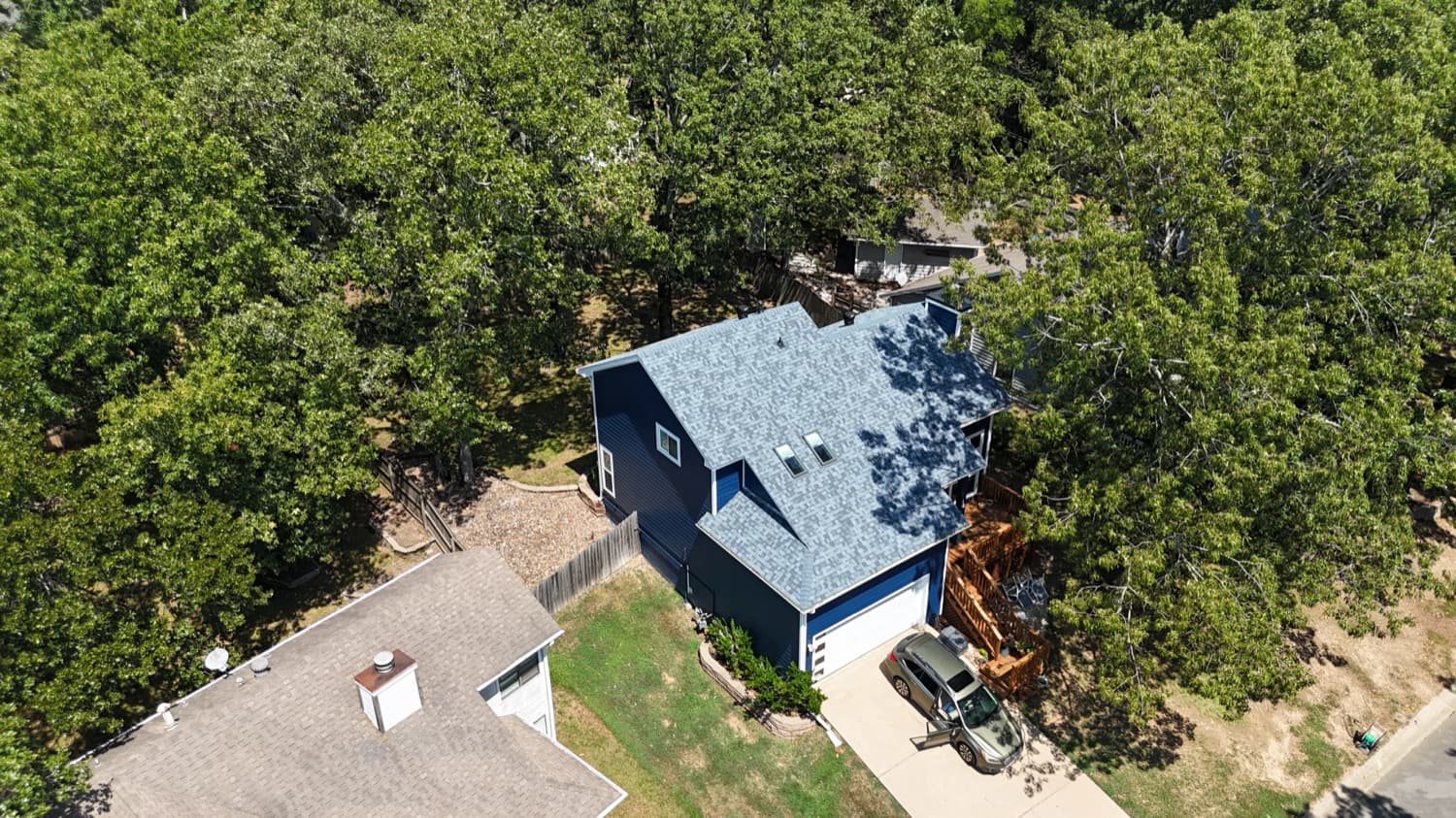 Two-story home with a new architectural shingle roof among the trees